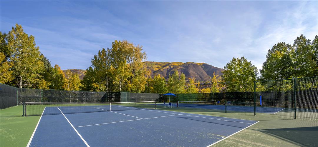 Blue tennis court with white court lines and a mountainside view