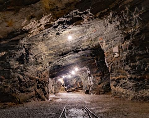 Picture of a mine with lights showing the way into the mine trail