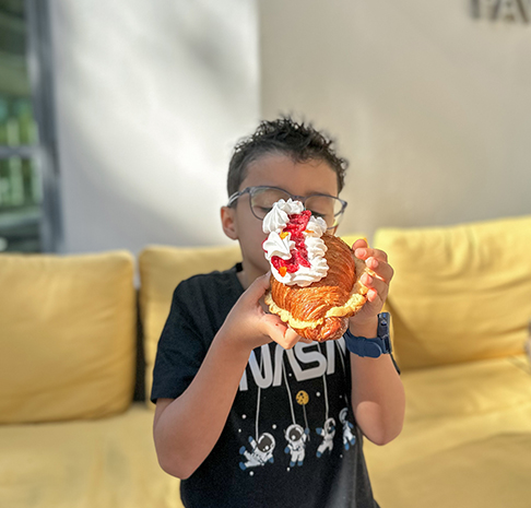 Child enjoying pastry at cafe