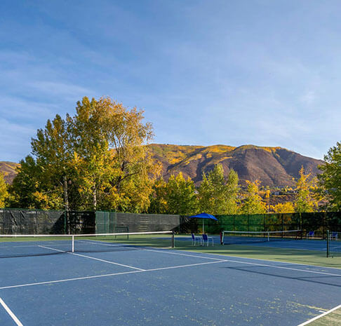 Blue tennis courts with mountainside view in autumn