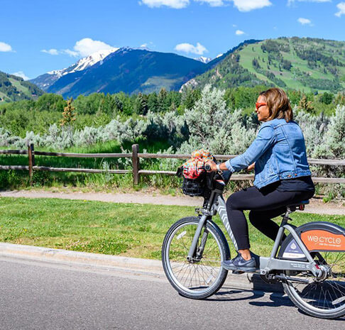 Woman cycling through Aspen using free bike