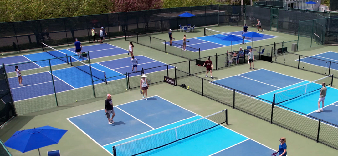 Blue tennis court with white court lines and a mountainside view