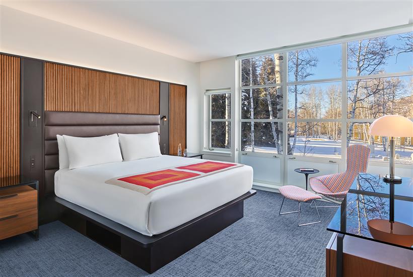 Mountain View One Bedroom Suite with a wall of windows, a sitting chair, and a king-sized bed