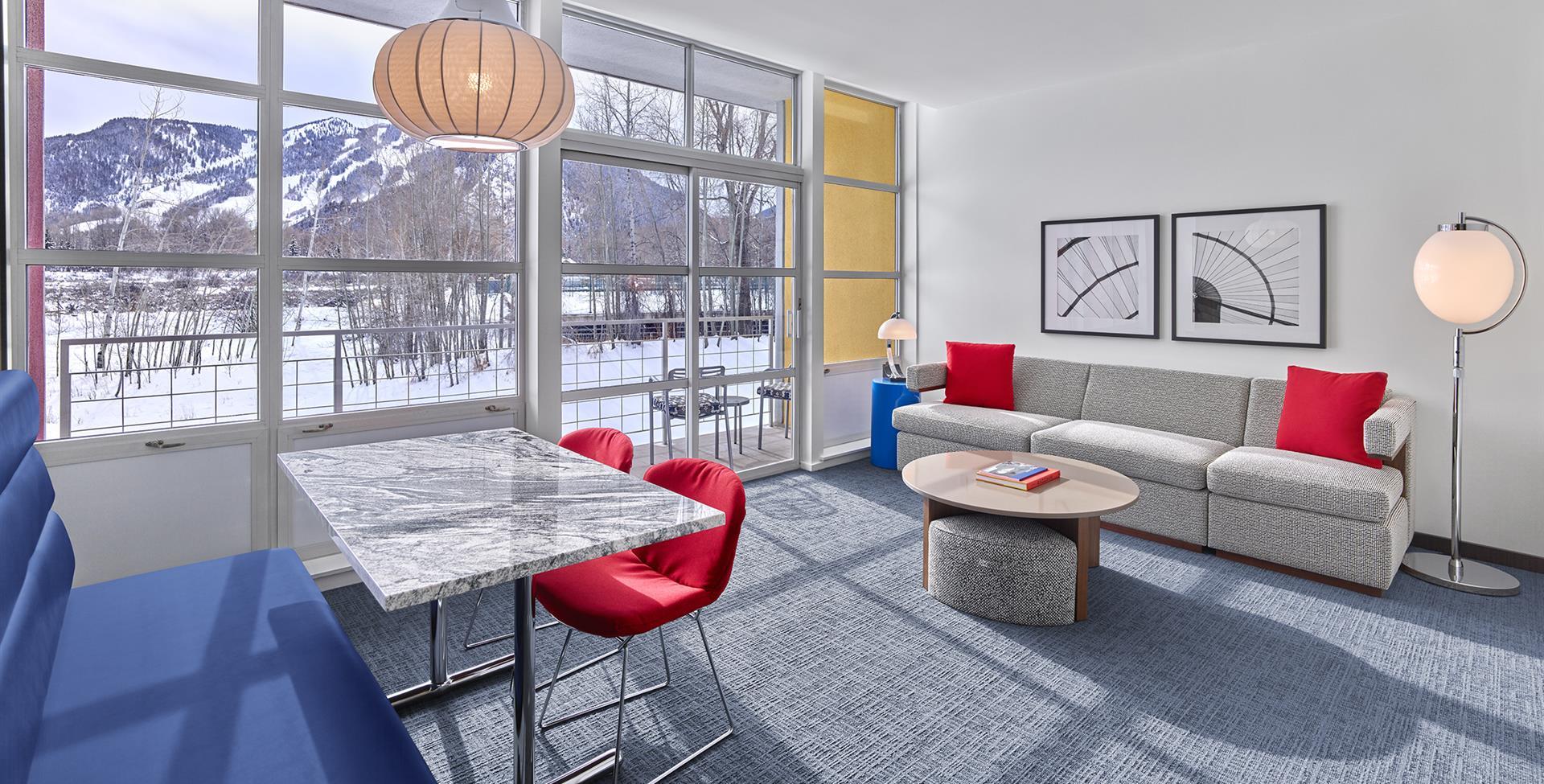 Suite with wall of windows, a couch, and a dining area in winter