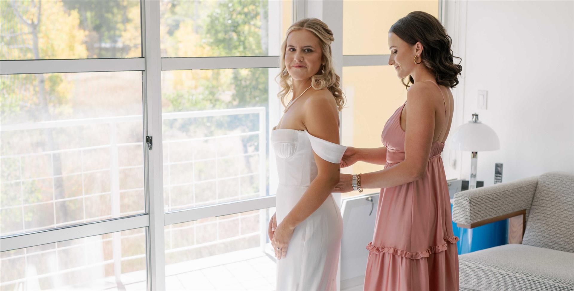 bride and bridesmaid in room getting ready