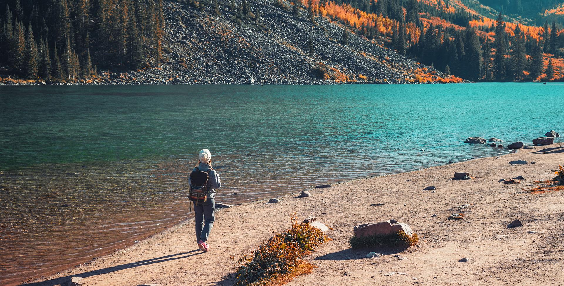 A lone figure standing on the tranquil coast of a lake