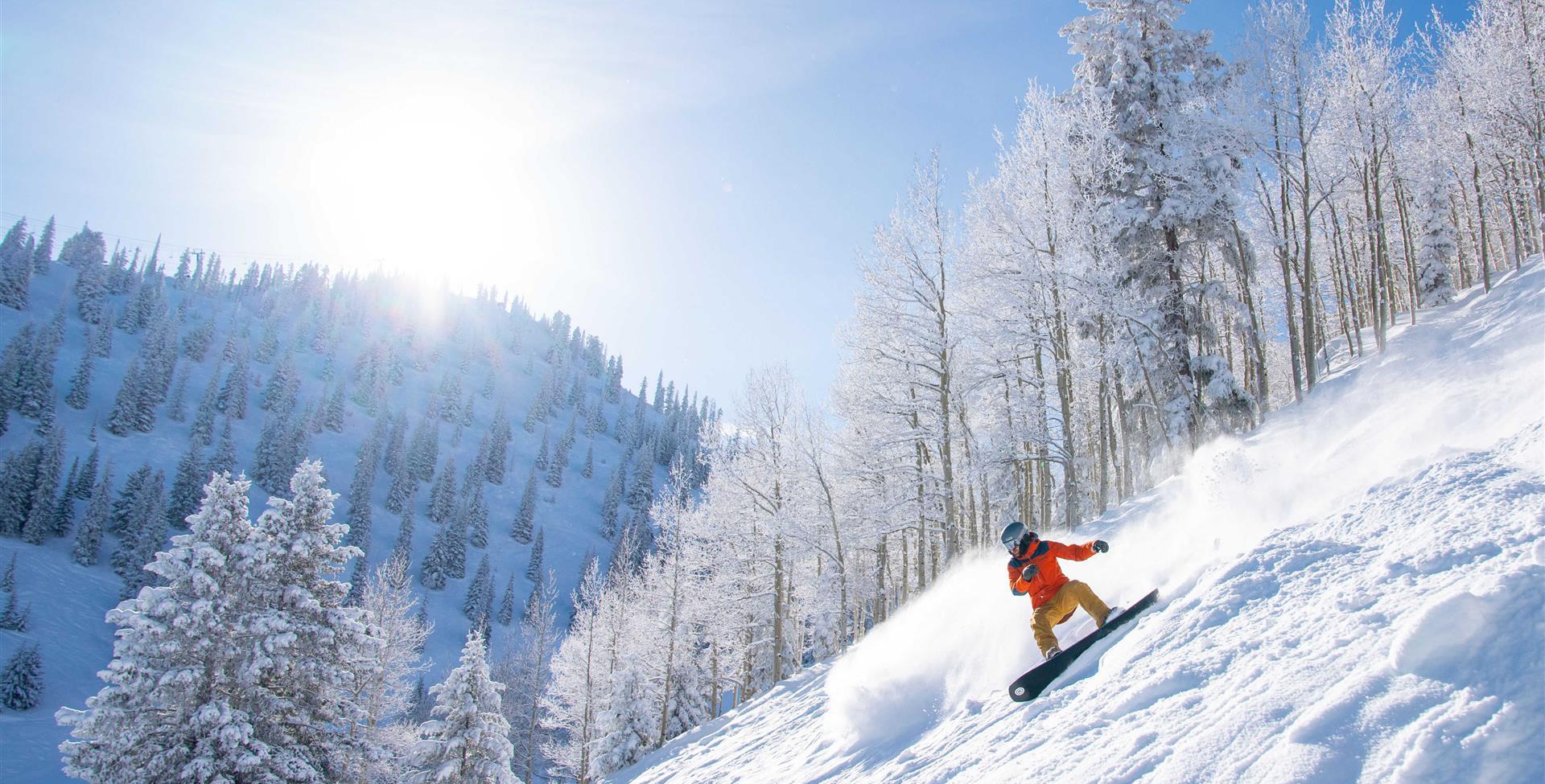 Individuals skiing down the hill on snowboards